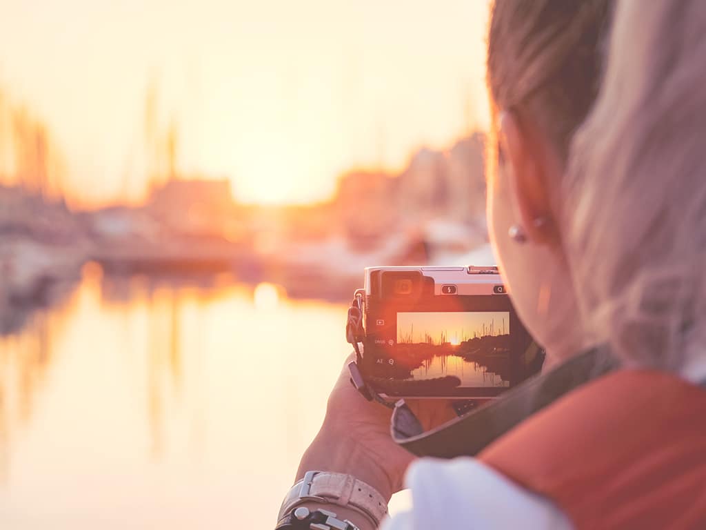 Frau mit Kamera fotografiert einen Hafen